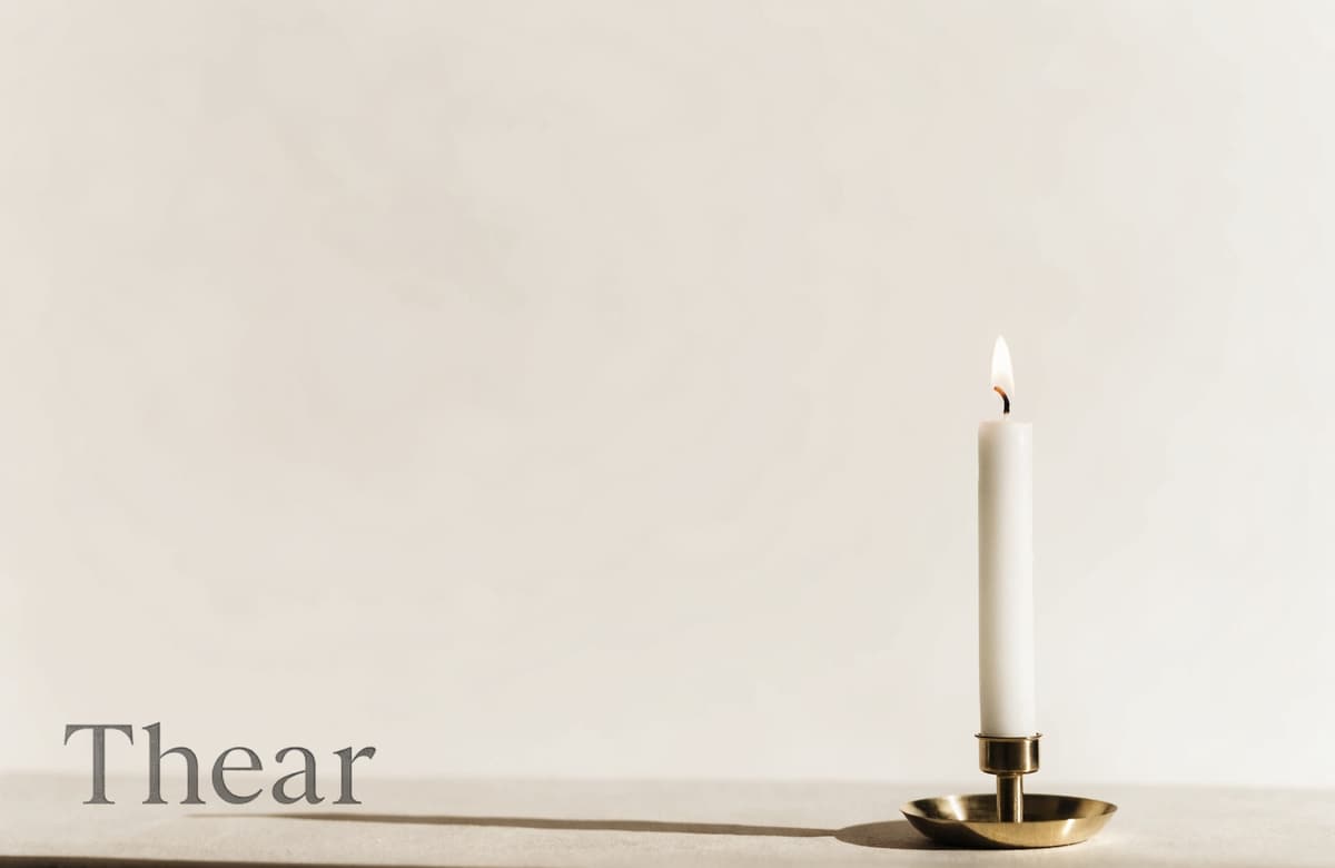 넓은 여백 가운데 홀로 켜진 촛불 하나 — 아래에 TheAr 워드마크