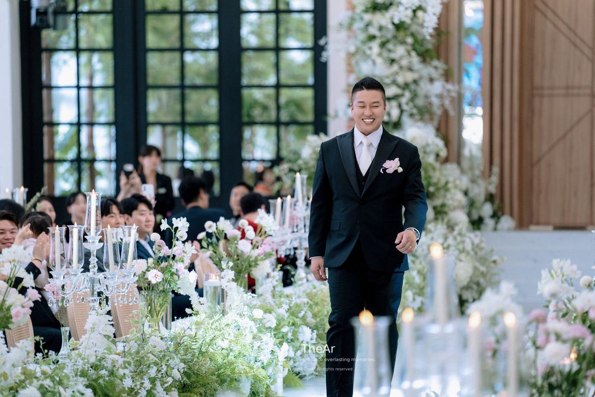격자창으로 빛이 드는 분당 바실리움 버진로드를 하객 사이로 걸어가는 신랑