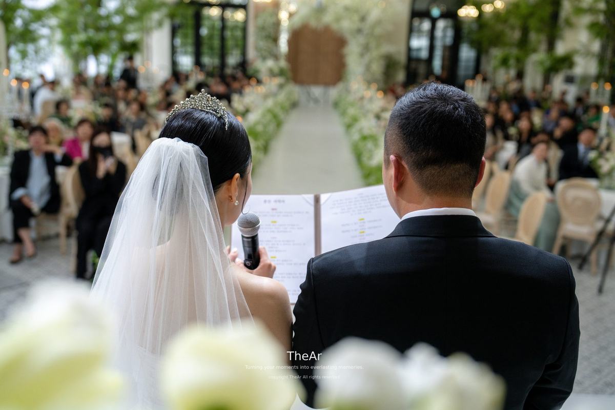 하객석을 마주 보고 서서 혼인서약서를 함께 펼쳐 든 신랑과 신부