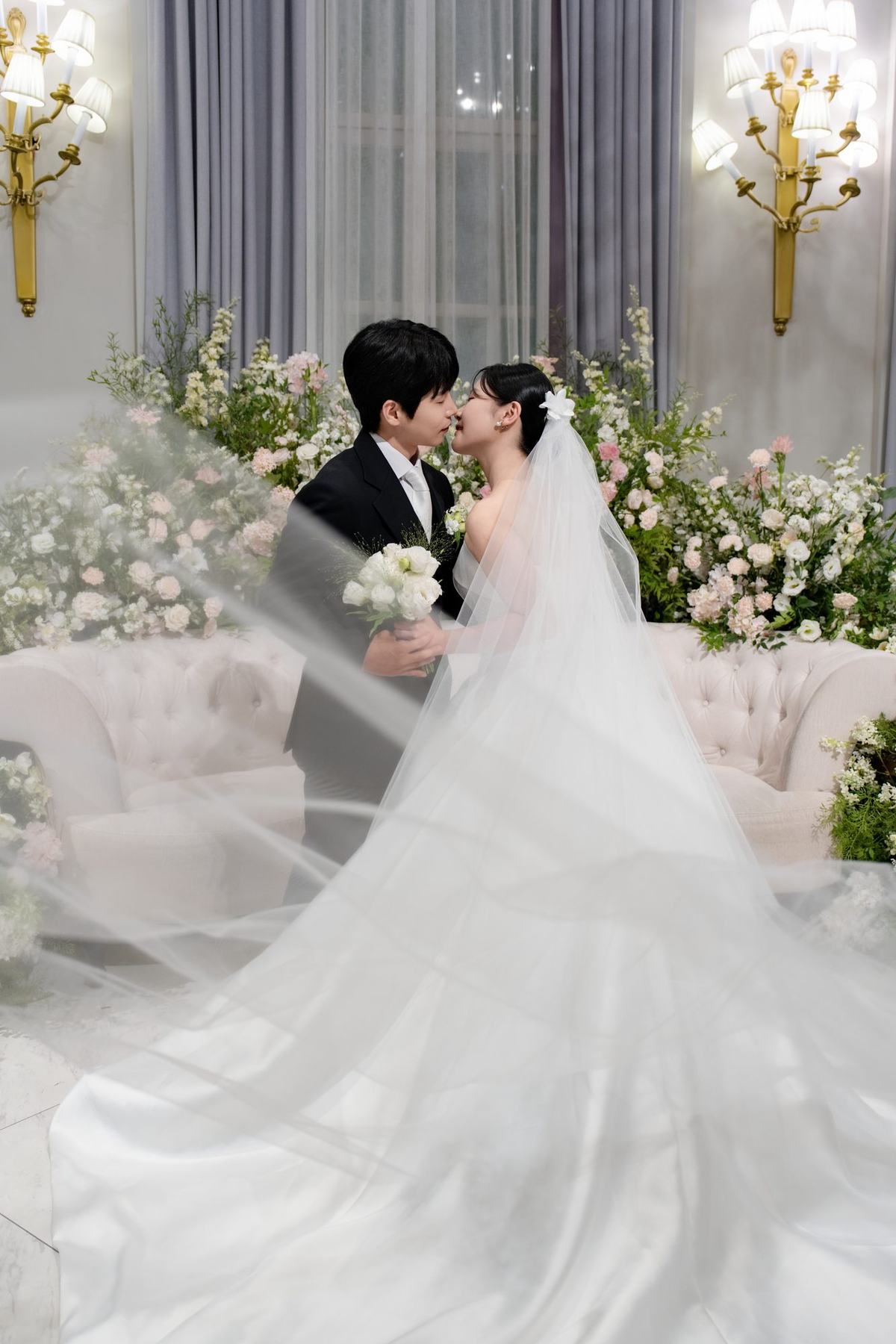 신부대기실 소파 앞에서 베일 너머로 이마를 맞댄 신랑과 신부