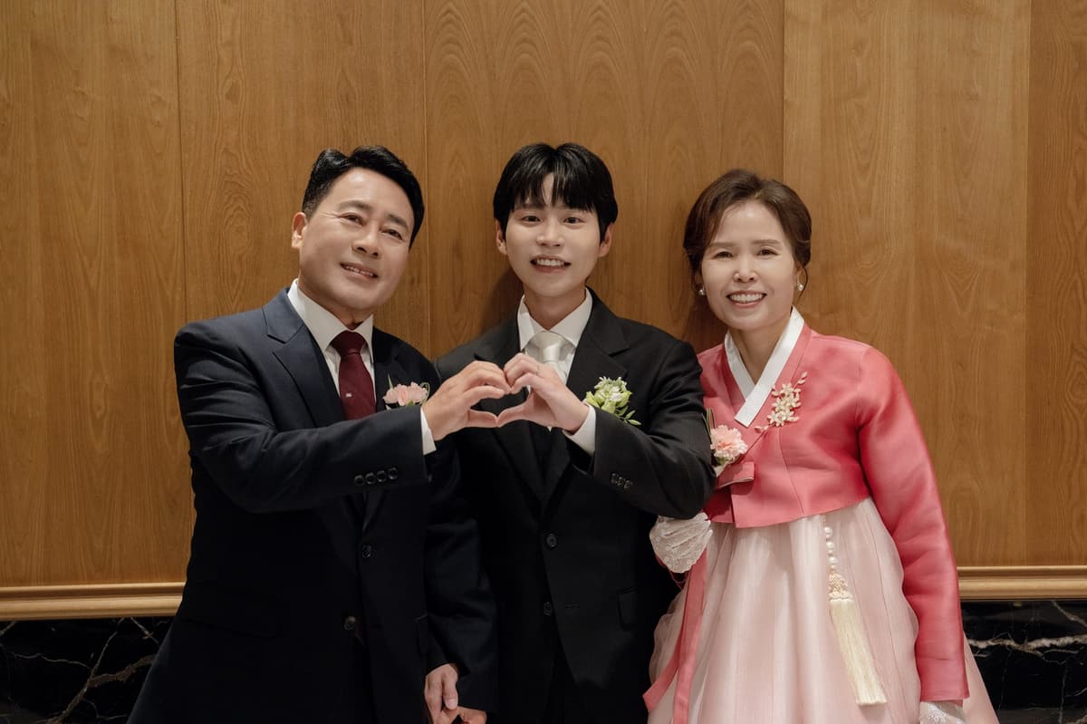 양가 부모님 사이에 선 신랑이 어머니·아버지와 함께 손하트를 만든다