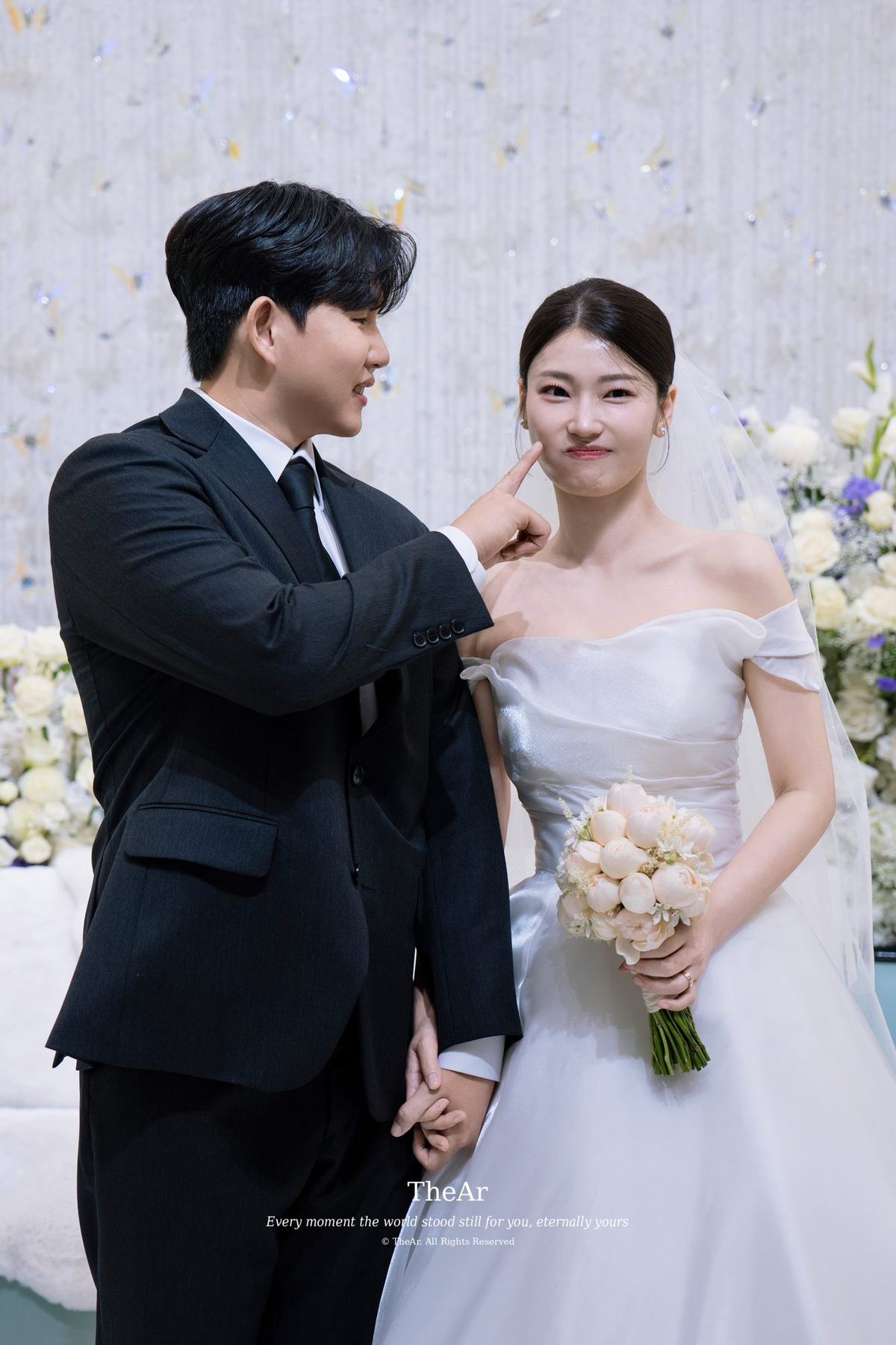 대기실에서 신부의 볼을 손끝으로 가리키며 장난을 거는 신랑과 웃음을 참는 신부