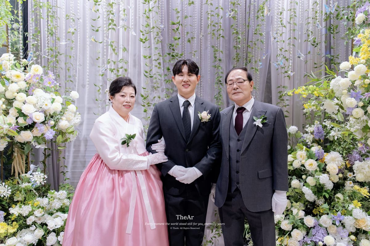 꽃 커튼을 배경으로 한복 차림의 어머니, 아버지와 나란히 선 신랑