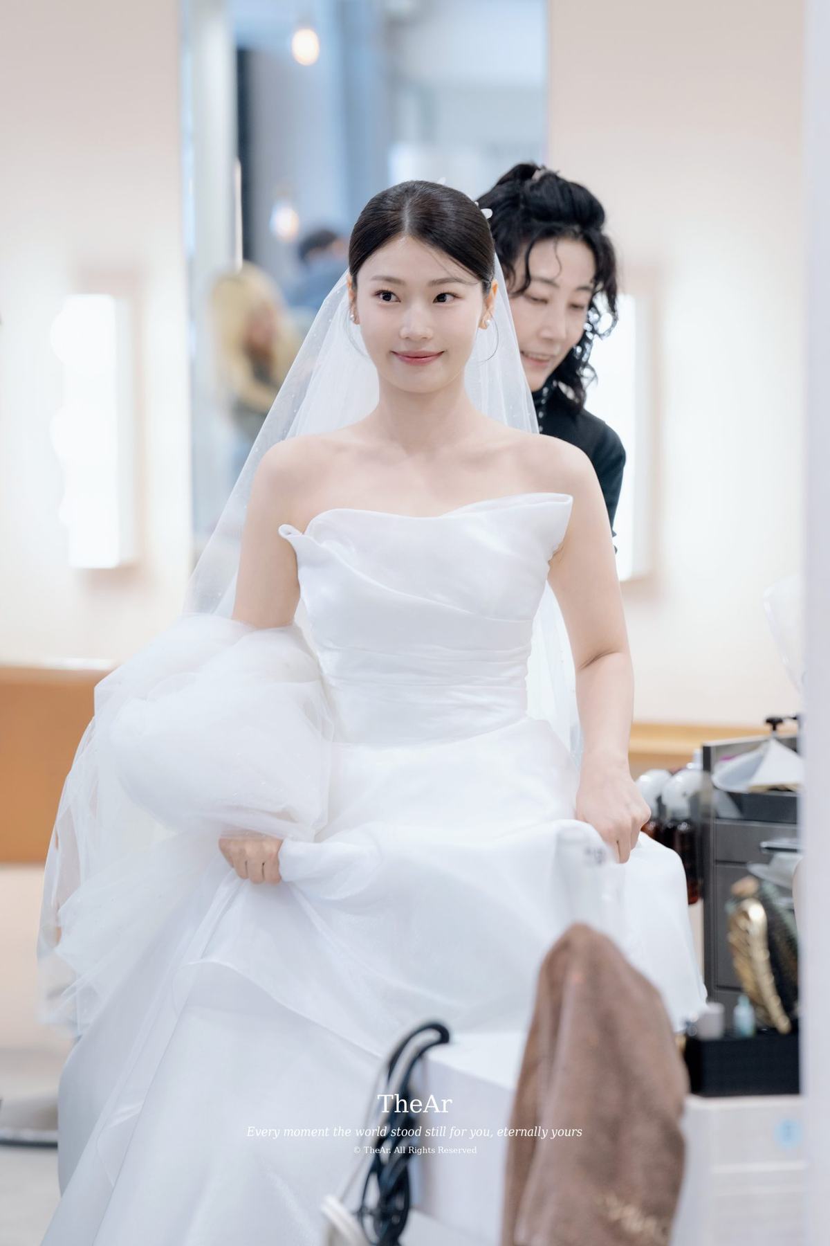 드레스 자락을 두 손으로 모아 쥐고 메이크업샵을 나서려 일어선 신부