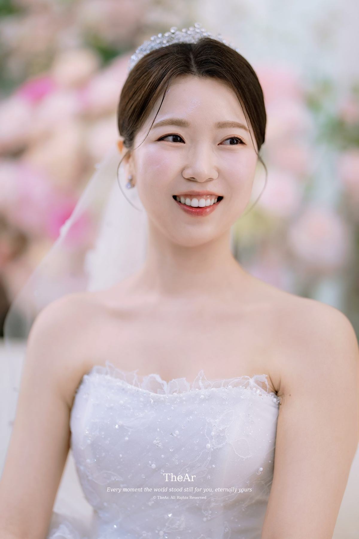 L65 가든홀 신부대기실에서 분홍 꽃 너머로 환하게 웃는 신부의 단독 컷