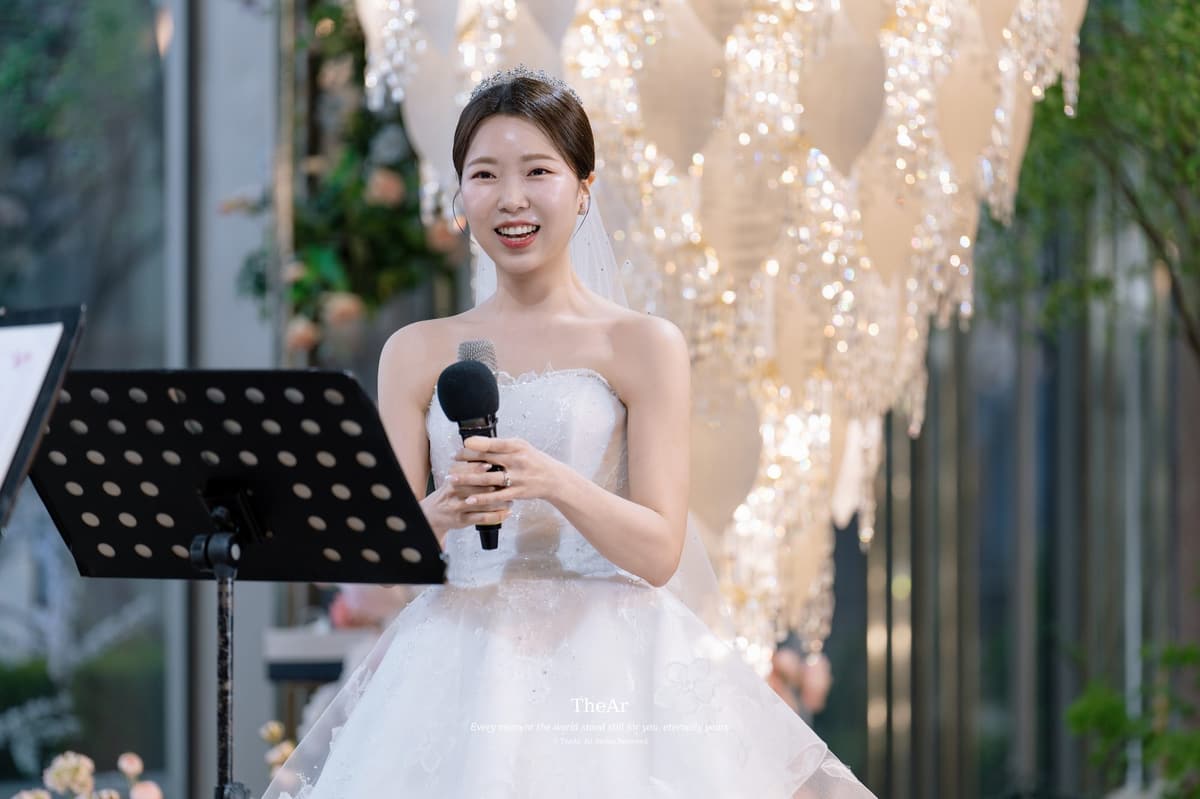 L65 가든홀 샹들리에 앞에서 마이크를 들고 노래하는 신부