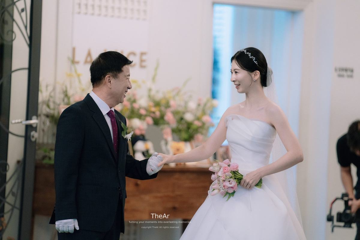 명동 라루체 웨딩홀 입장 직전 라루체 사인 앞에서 아버지와 손을 맞잡고 마주 보는 신부