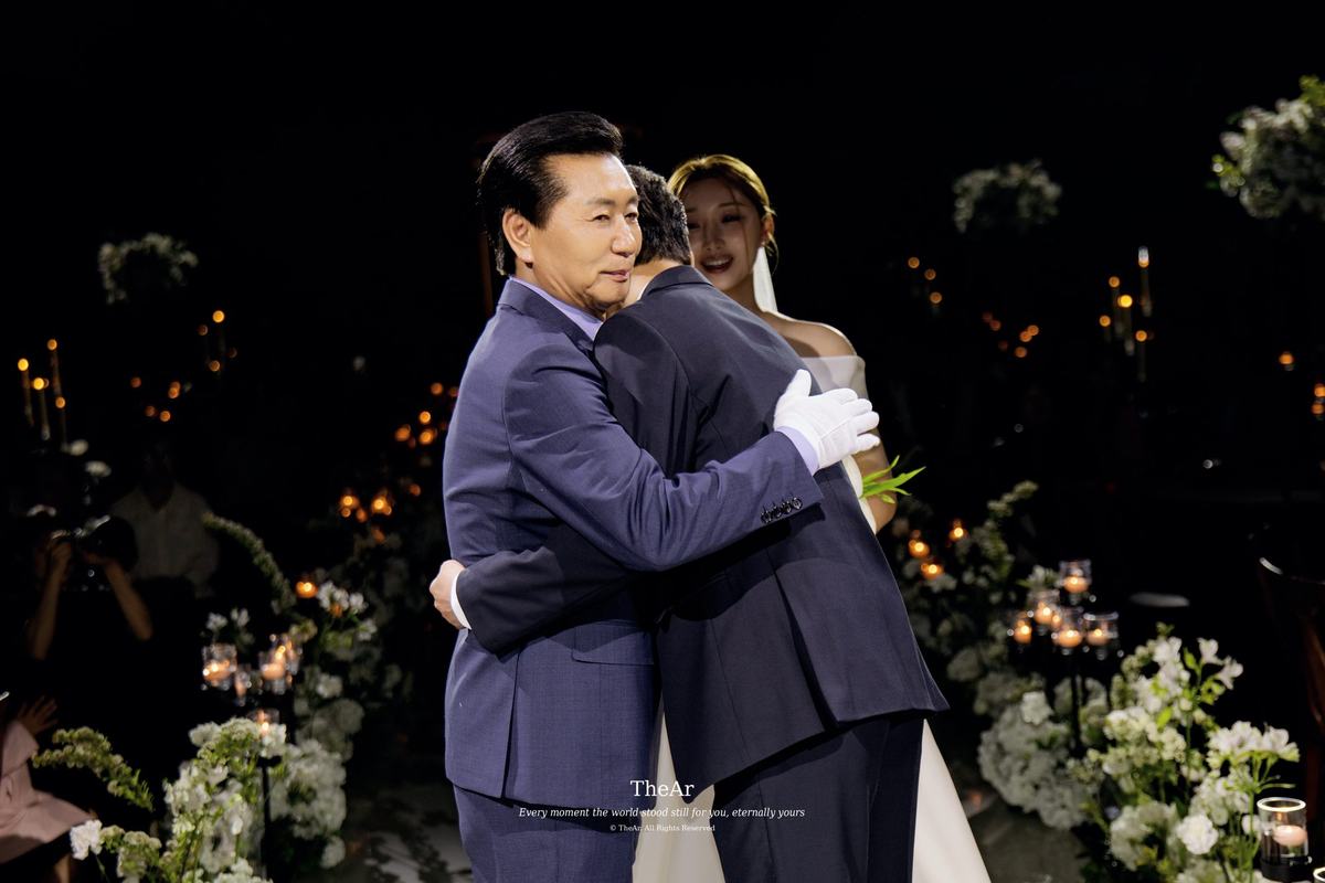 서울웨딩타워 컨벤션홀 단상에서 신부를 데려온 아버지와 마주 안는 신랑