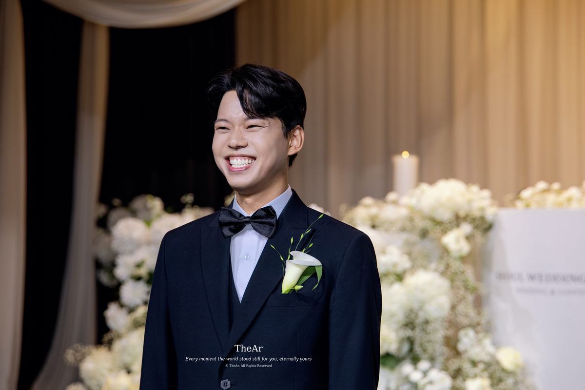 서울웨딩타워 컨벤션홀 단상 앞에서 하객을 바라보며 환하게 웃는 신랑