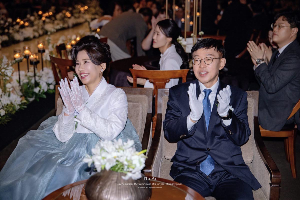 서울웨딩타워 컨벤션홀 혼주석에서 흰 장갑을 끼고 박수를 보내는 양가 부모