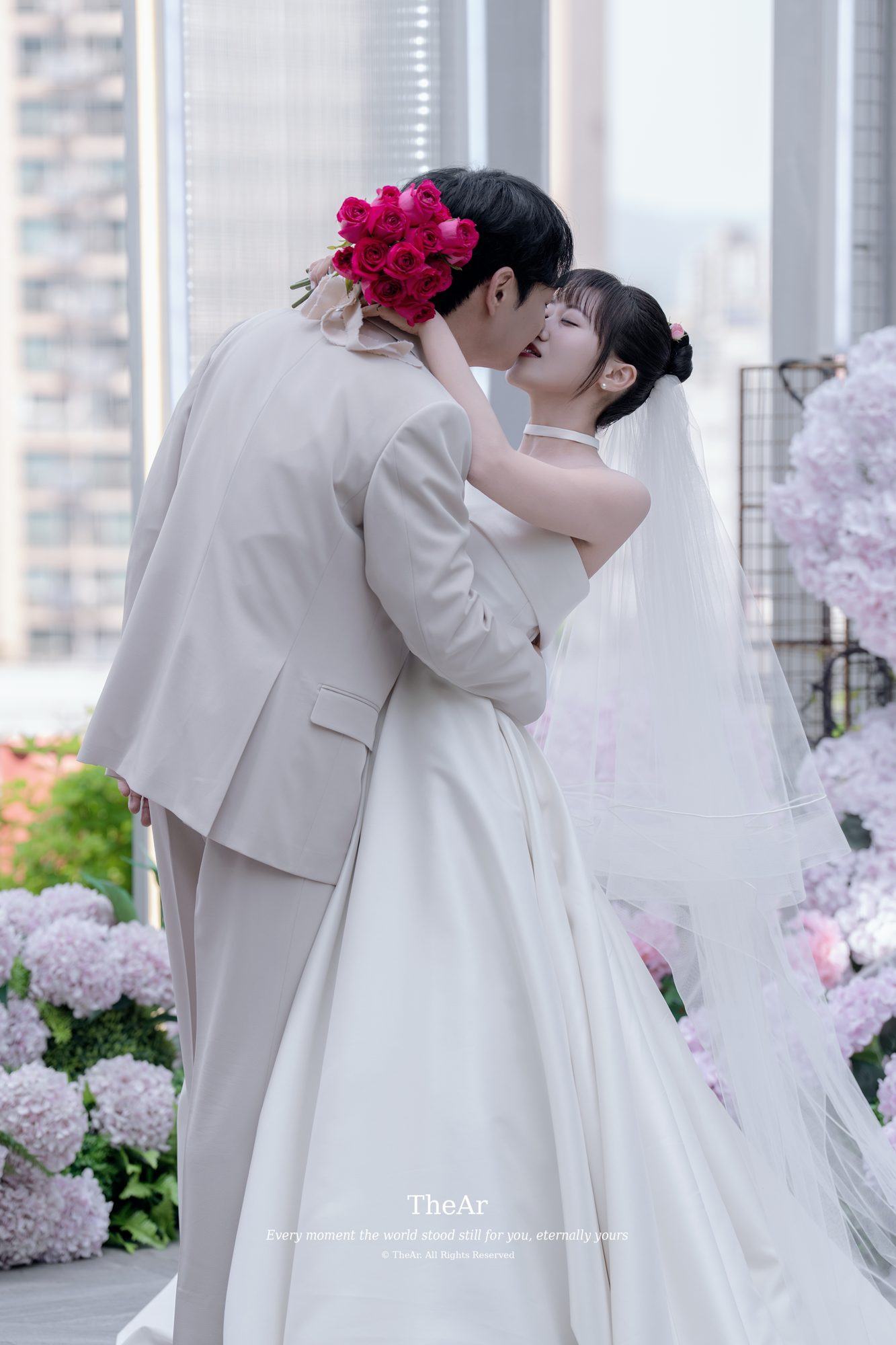 도시가 내려다보이는 루프탑 야외 예식장에서 수국에 둘러싸여 입을 맞추는 신랑과 신부